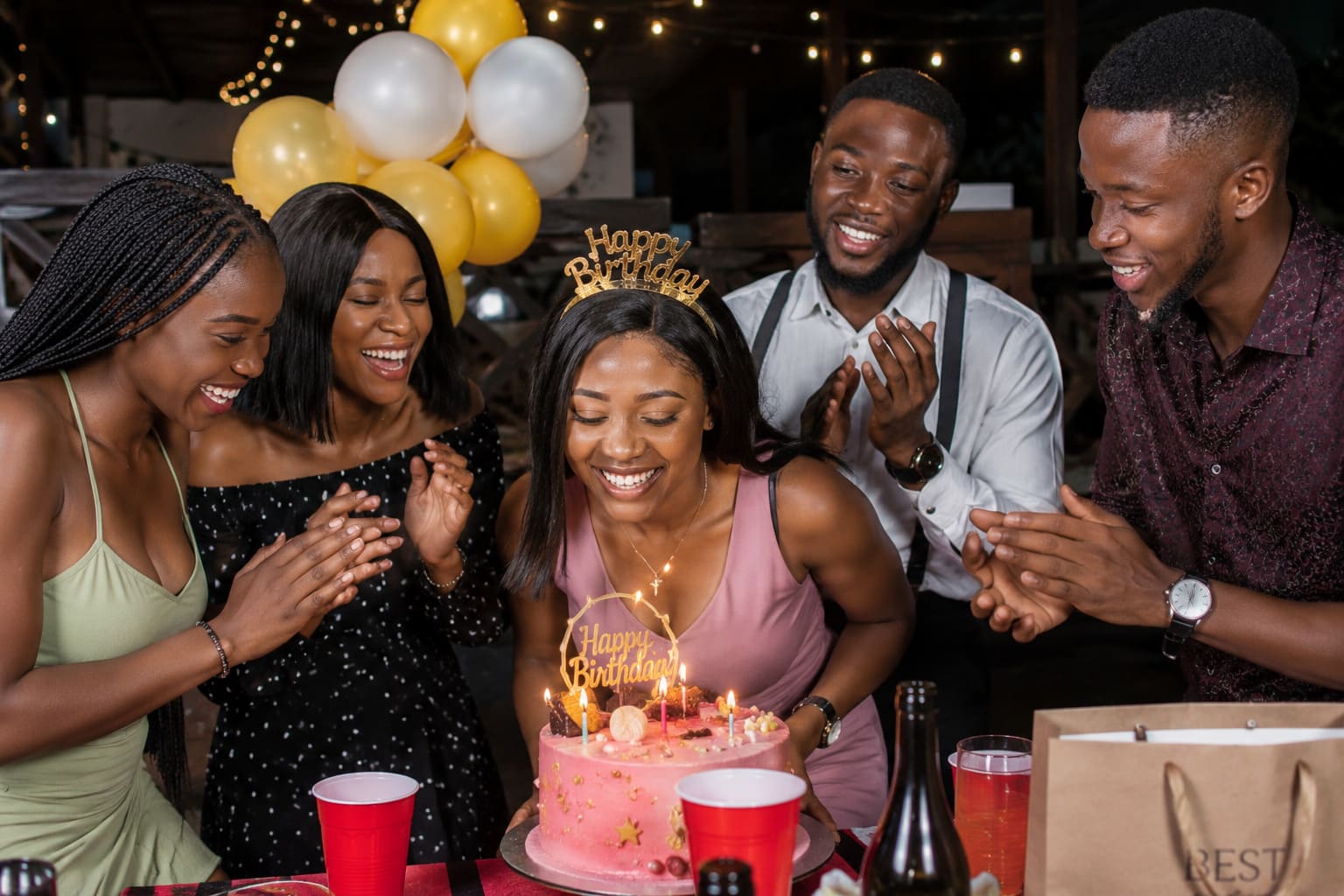 Friends celebrating a birthday in Nigeria with a cake and balloons